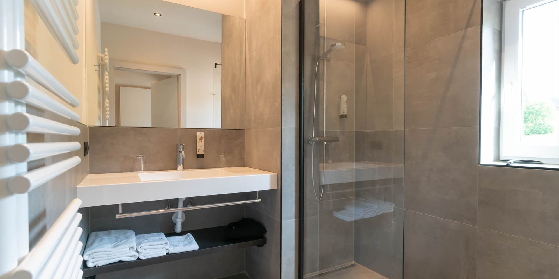 Großformatige, hellgraue Wand- und Bodenliesen lassen den Raum größer erscheinen Großformatige, hellgraue Wand- und Bodenliesen lassen den Raum größer erscheinen