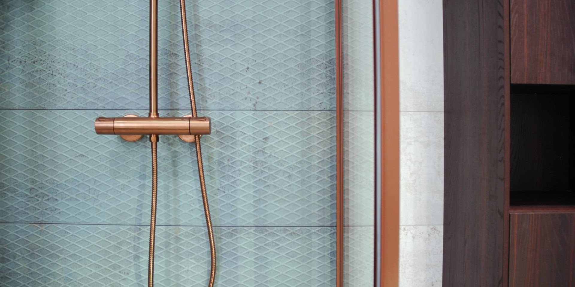 Türkisfarbene Badezimmerfliesen und kupferfarbene Armaturen